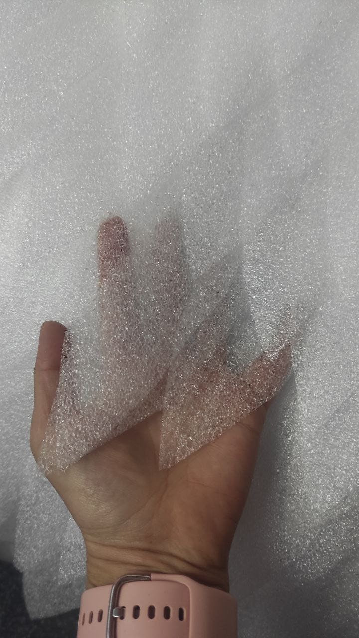 May include: A close-up of a white, textured, bubble wrap sheet. The sheet is being held in a hand, and the bubbles are visible.