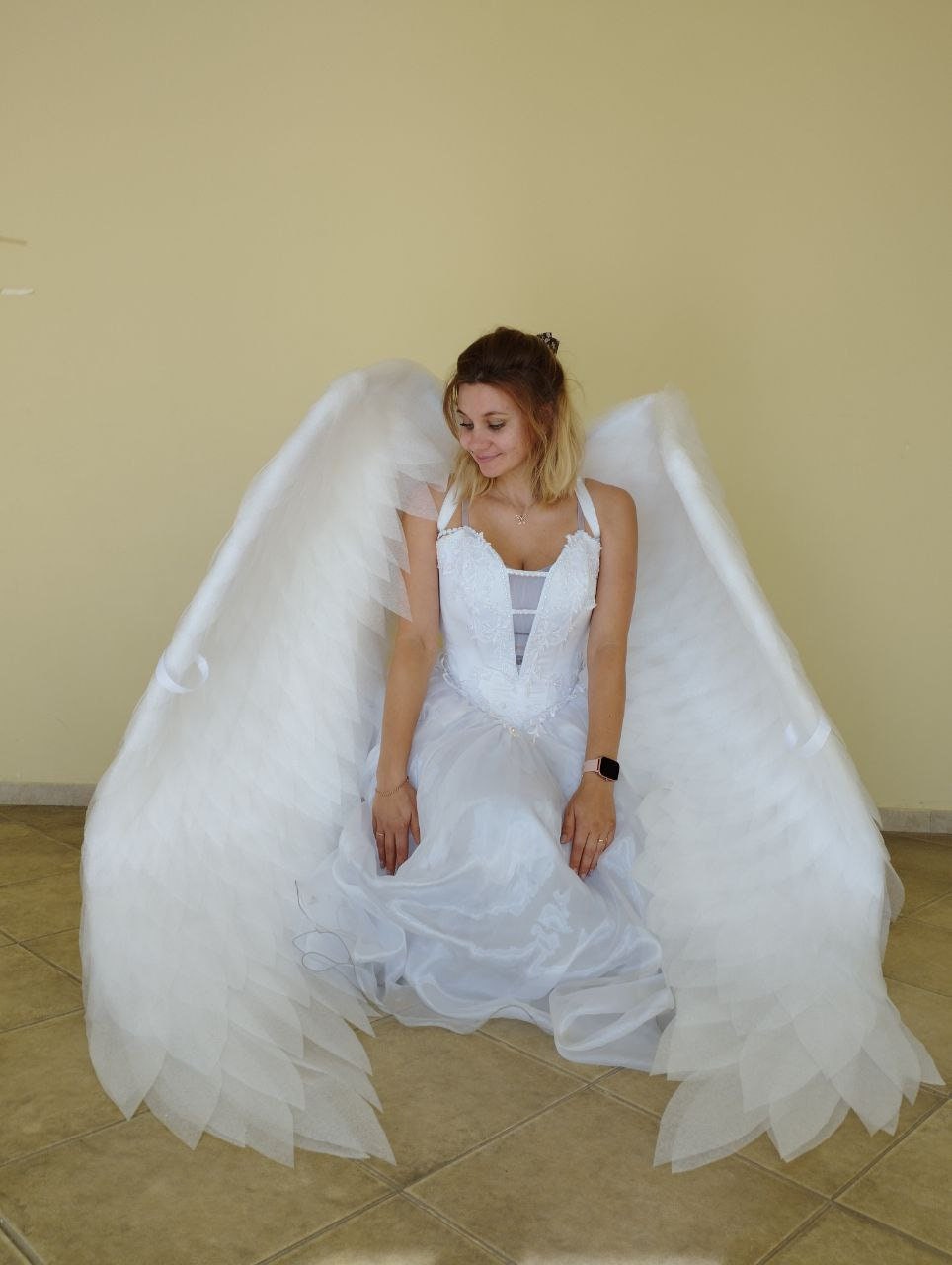 May include: A white angel costume featuring large, feathery wings and a matching dress. The dress has a detailed bodice and a flowing skirt. The wings are attached to the back, creating a dramatic effect. The costume is designed for a theatrical or costume event.