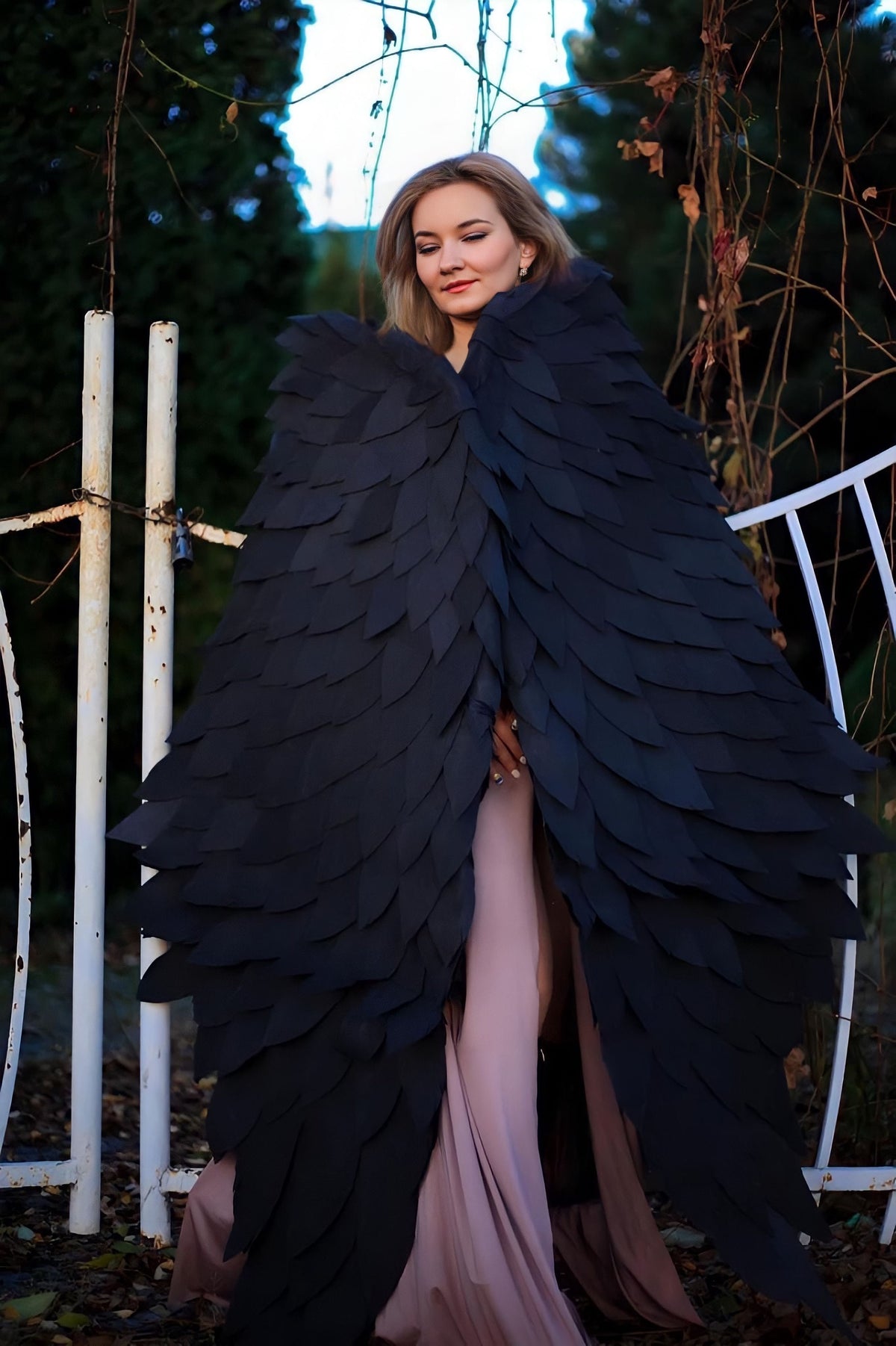 May include: A woman wearing a long, flowing pink dress with large, black feathered wings.
