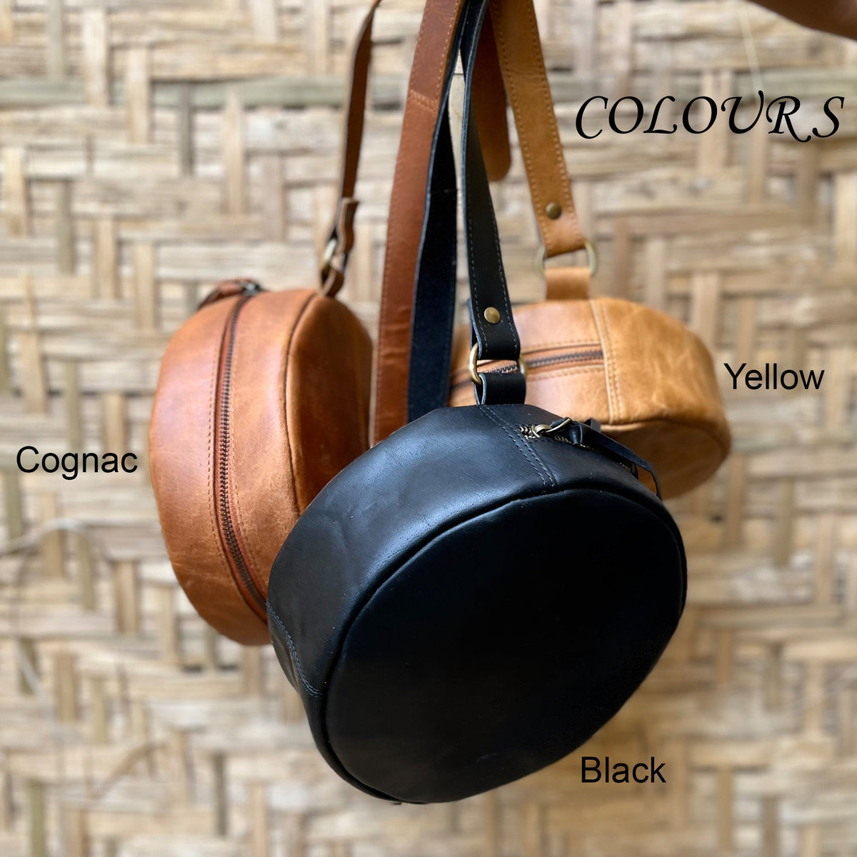 May include: Three round leather bags in cognac, black, and yellow. The bags have a zipper closure and a strap. The text "COLOURS" is written in white on a brown background. The text "Cognac", "Black", and "Yellow" are written below the bags.