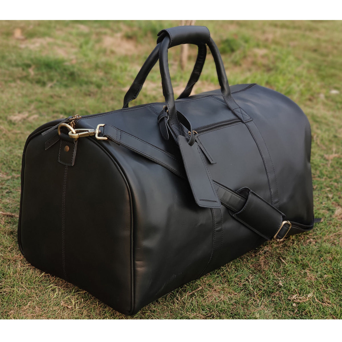 May include: A black leather duffel bag with a top handle and a shoulder strap. The bag has a zipper closure and a luggage tag.
