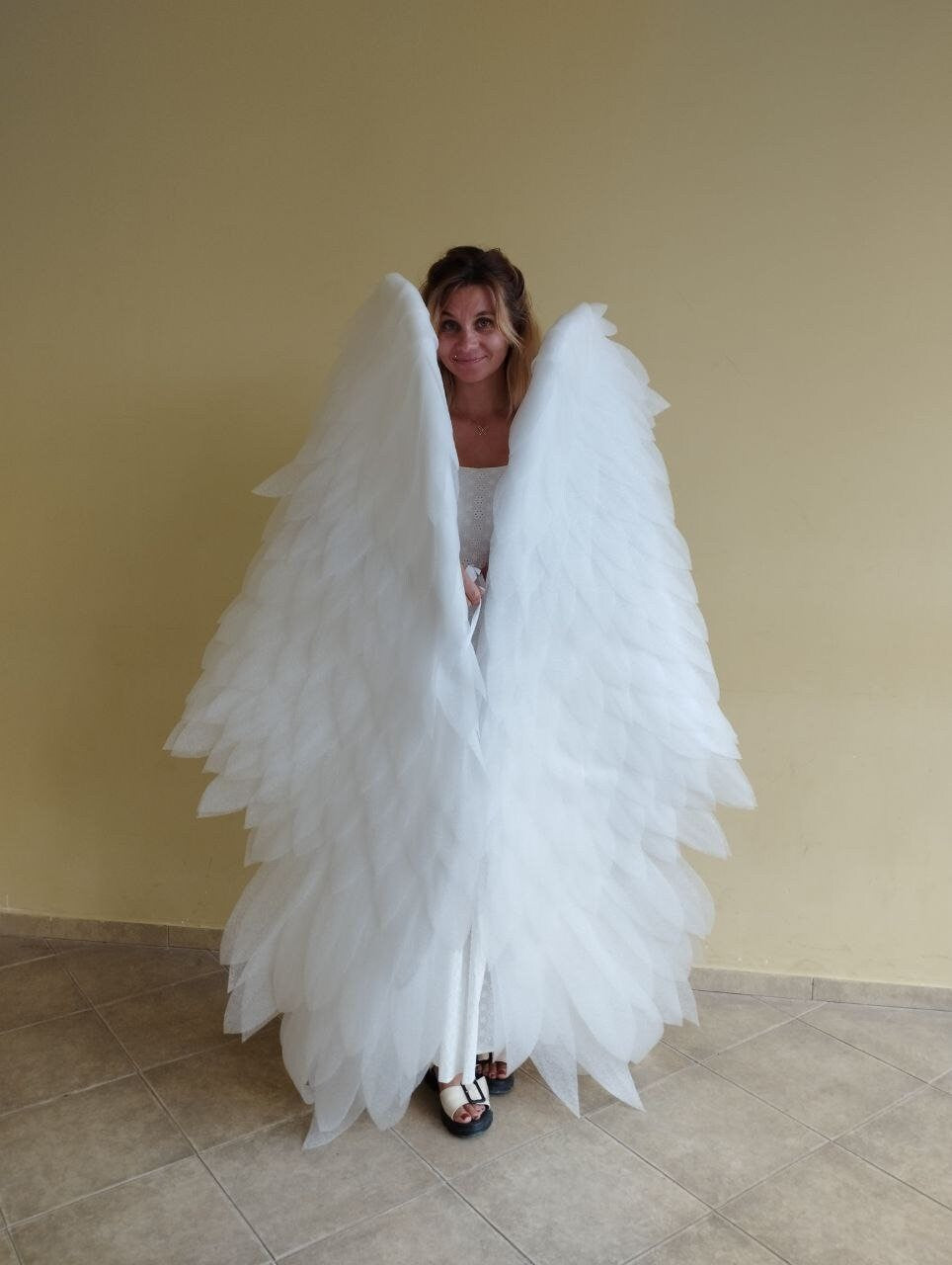 May include: A woman wearing a white costume with large white angel wings.