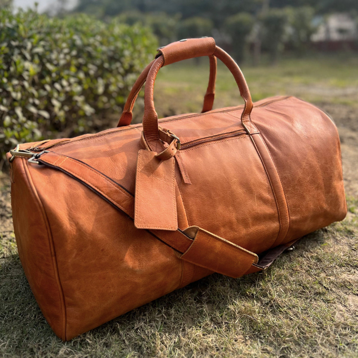 May include: A brown leather duffel bag with a top handle and a shoulder strap. The bag has a zipper closure and a luggage tag.