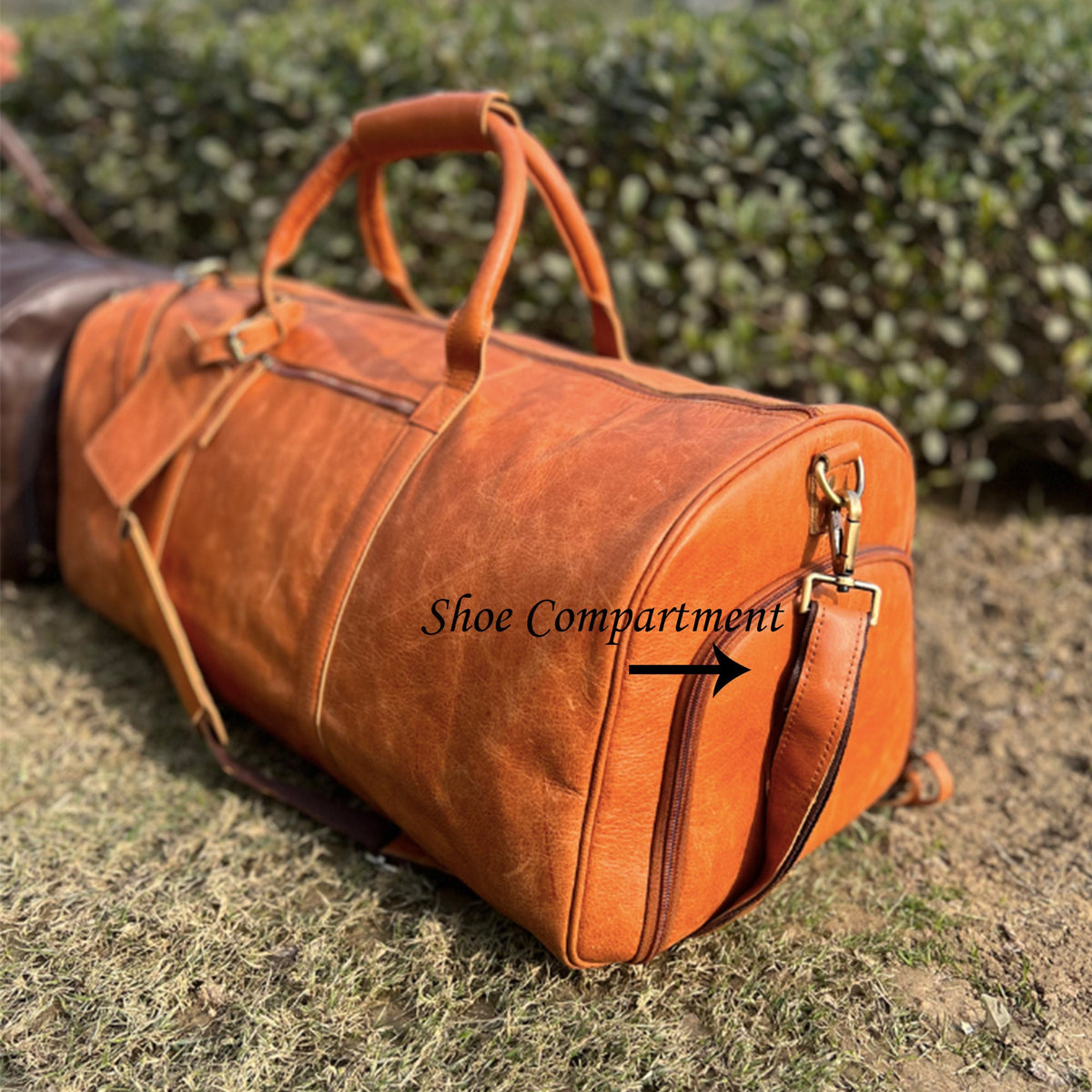 May include: A brown leather duffel bag with a zippered closure and a separate shoe compartment. The bag has a top handle and a shoulder strap.