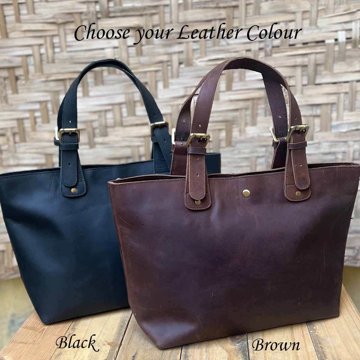May include: Two leather tote bags, one black and one brown, with gold buckles and a gold button on the front. The text "Choose your Leather Colour" is at the top of the image. The text "Black" is below the black bag and the text "Brown" is below the brown bag.