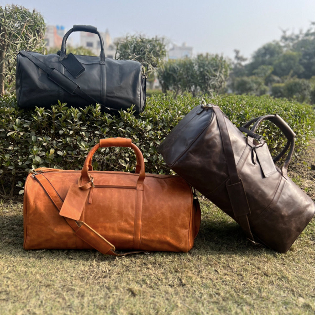 May include: Three leather travel bags in different colors: black, brown, and tan. The bags have a classic design with a top handle and a shoulder strap.
