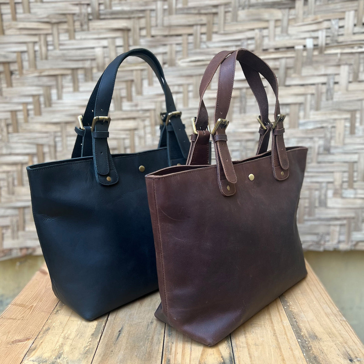 May include: Two leather tote bags, one black and one brown, with double straps and gold buckles.