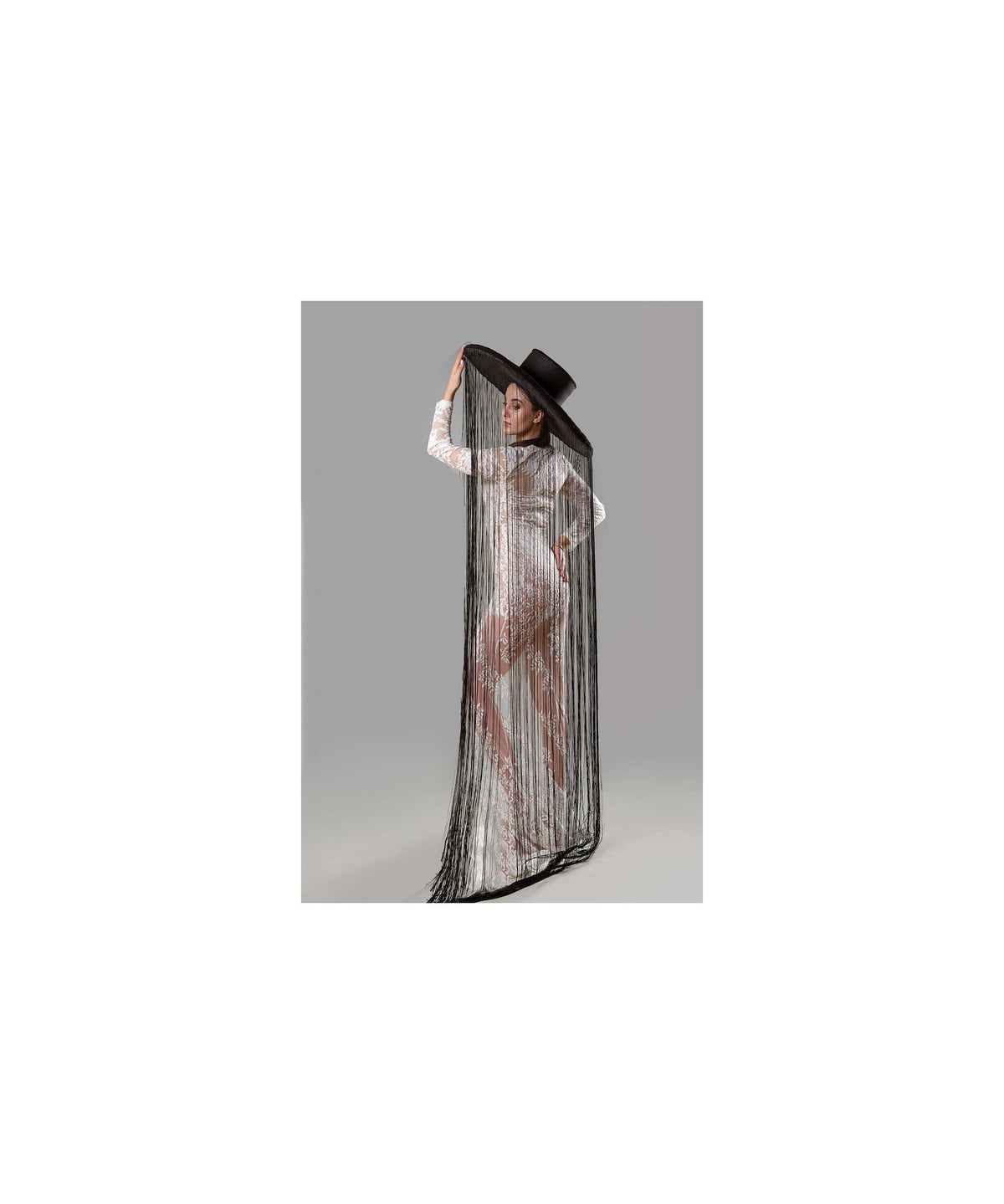May include: A woman wearing a white lace dress with a long black fringe shawl and a wide-brimmed black hat.