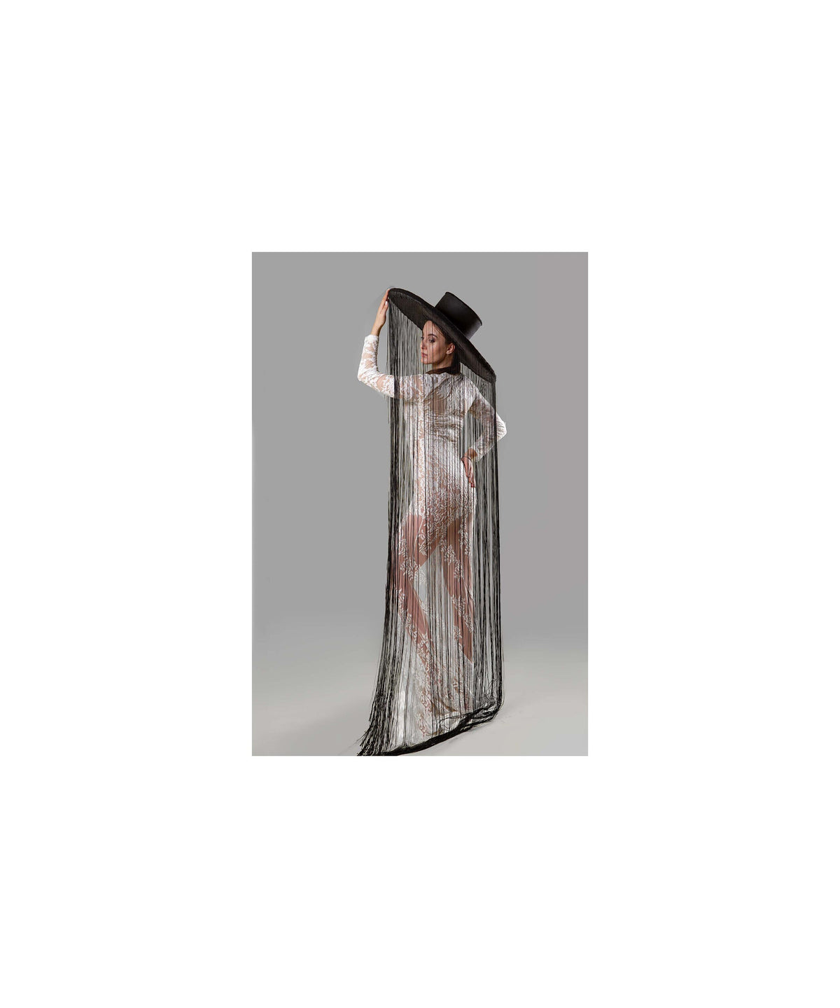 May include: A woman wearing a white lace dress with a long black fringe shawl and a wide-brimmed black hat.