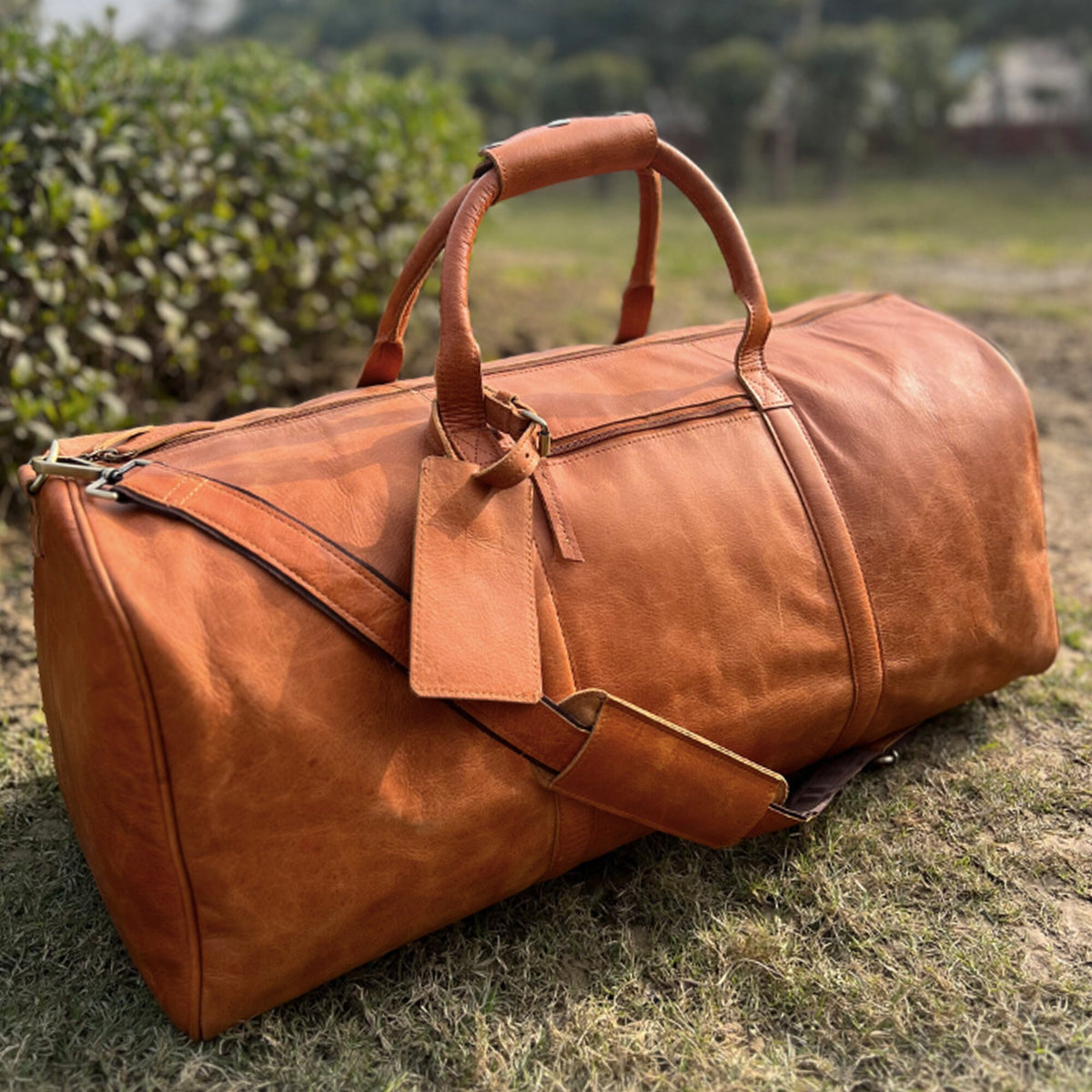 May include: A brown leather duffel bag with a top handle and a shoulder strap. The bag has a zipper closure and a luggage tag.
