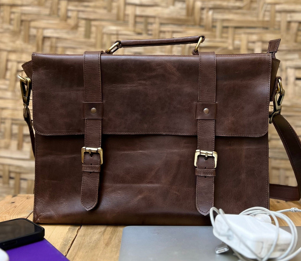May include: A brown leather briefcase with two adjustable straps and a buckle closure. The bag has a top handle and a long shoulder strap.