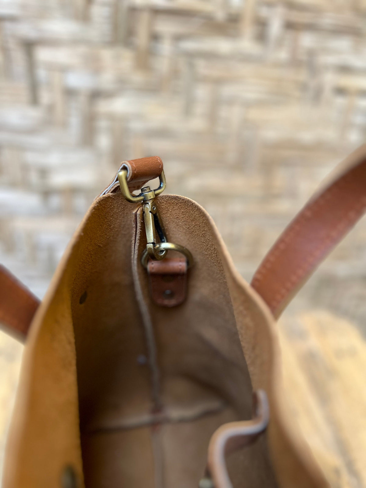 May include: A brown leather tote bag with a brass clasp and a brown leather strap. The bag is open and the inside is visible.