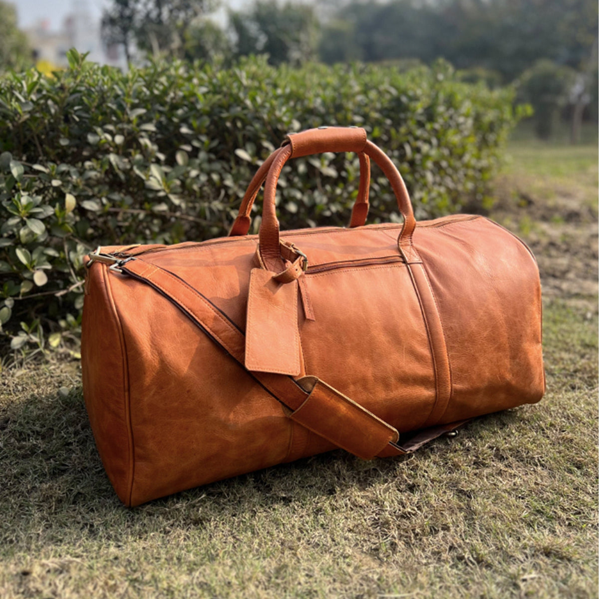 May include: A brown leather duffel bag with a top handle and a shoulder strap. The bag has a zipper closure and a luggage tag.