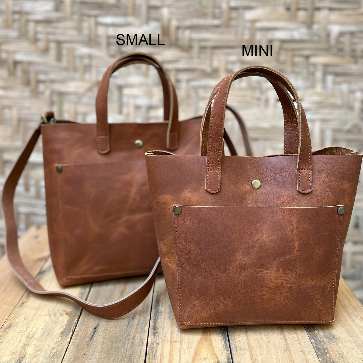 May include: Two brown leather tote bags, one labeled "SMALL" and the other labeled "MINI". Both bags have a single pocket on the front and a top handle.