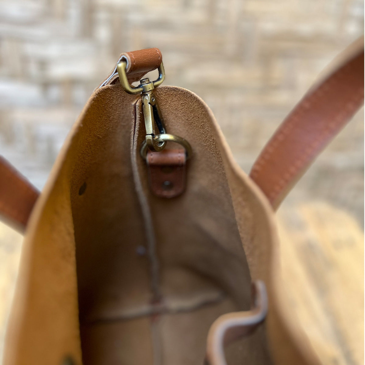 May include: A brown leather tote bag with a brass clasp and a brown leather strap. The bag is open and the inside is visible.