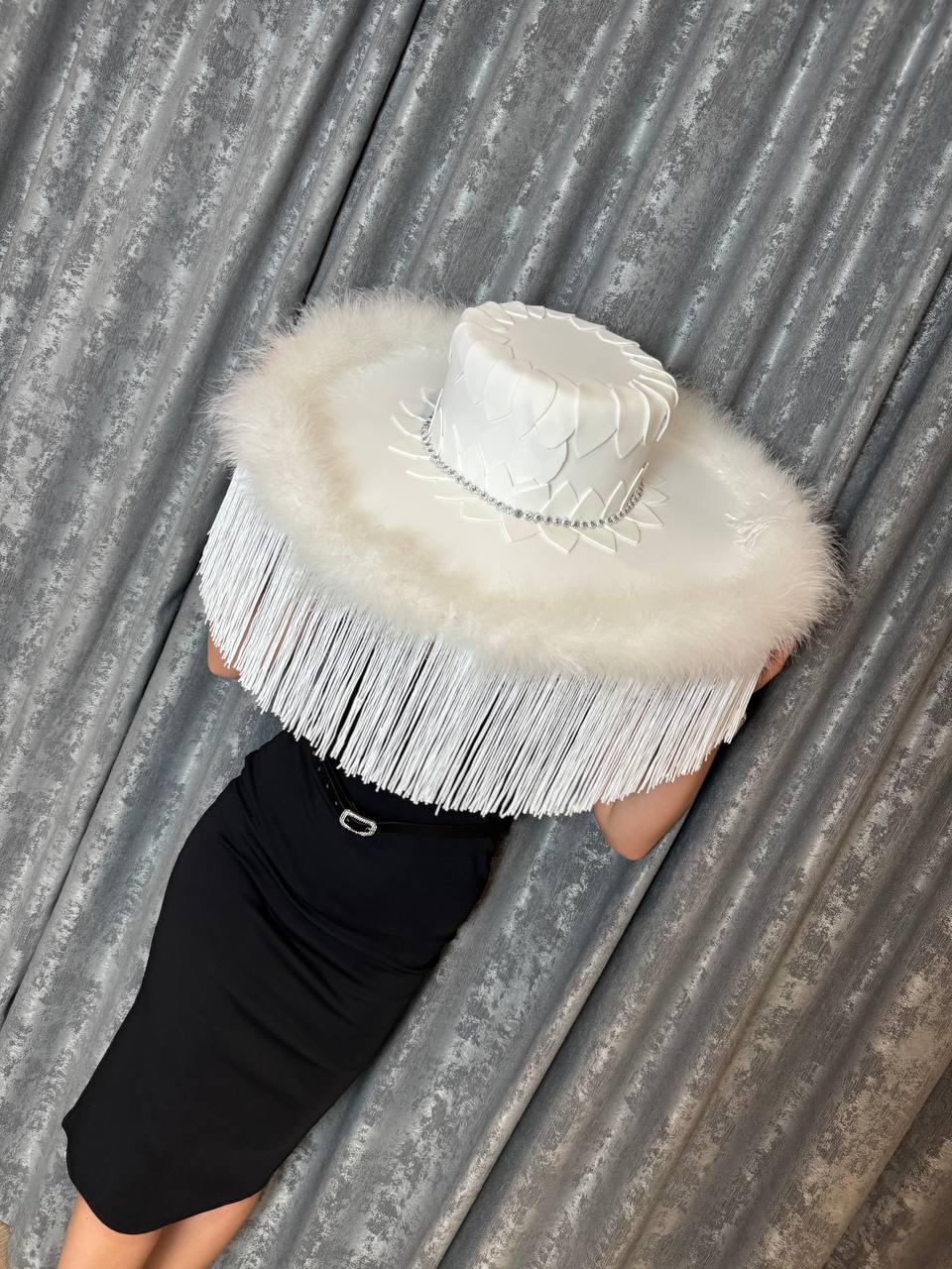 May include: A large white hat with a wide brim and a feathered trim. The hat is decorated with white flowers and rhinestones.