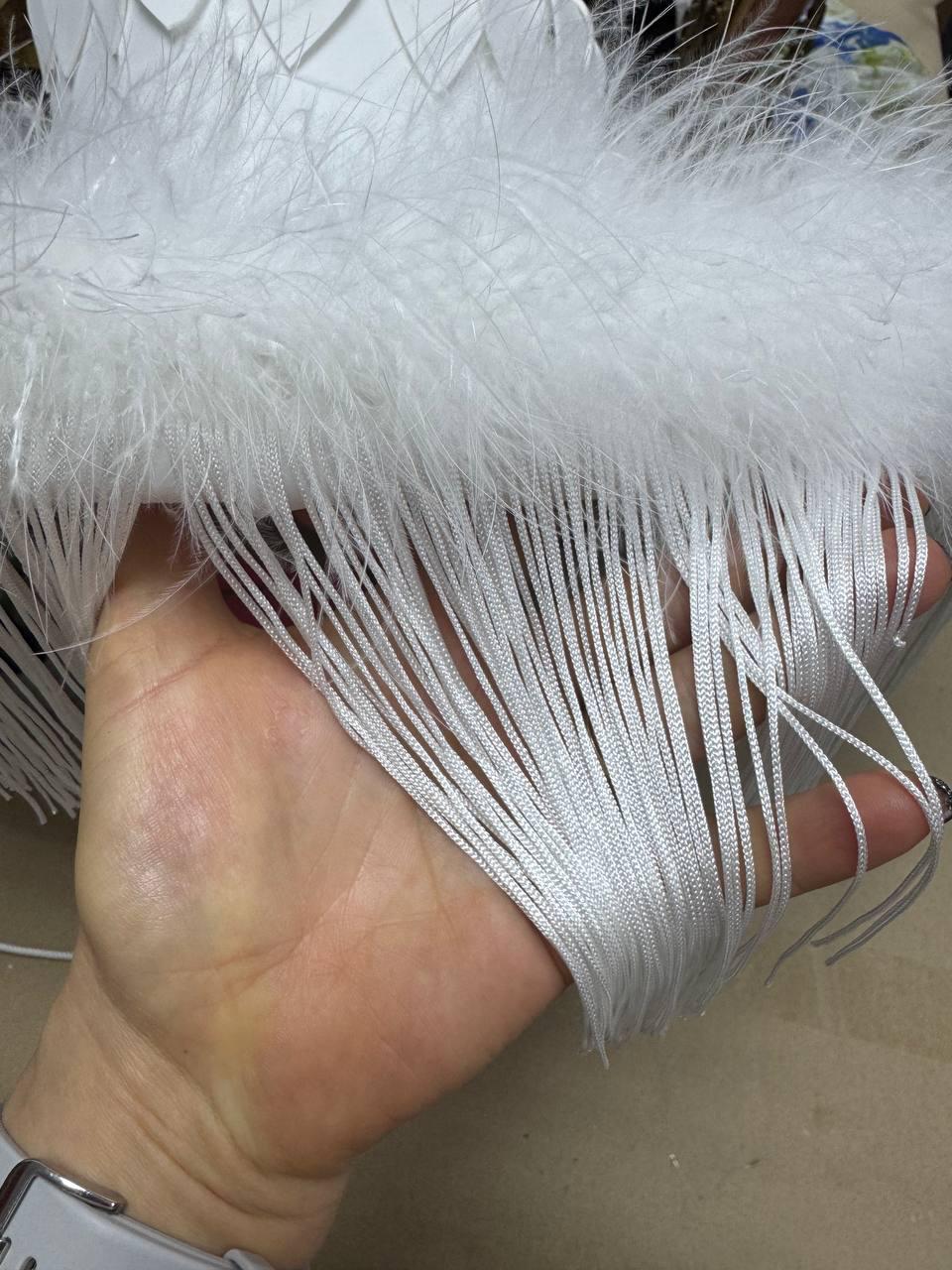 May include: White feather trim with a fringe of white cords. The trim is soft and fluffy.