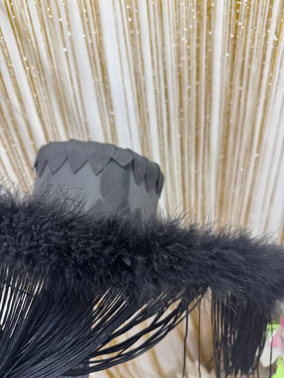 May include: Black feather trim with a fringe detail. The trim is made of soft, fluffy feathers and has a long, flowing fringe.