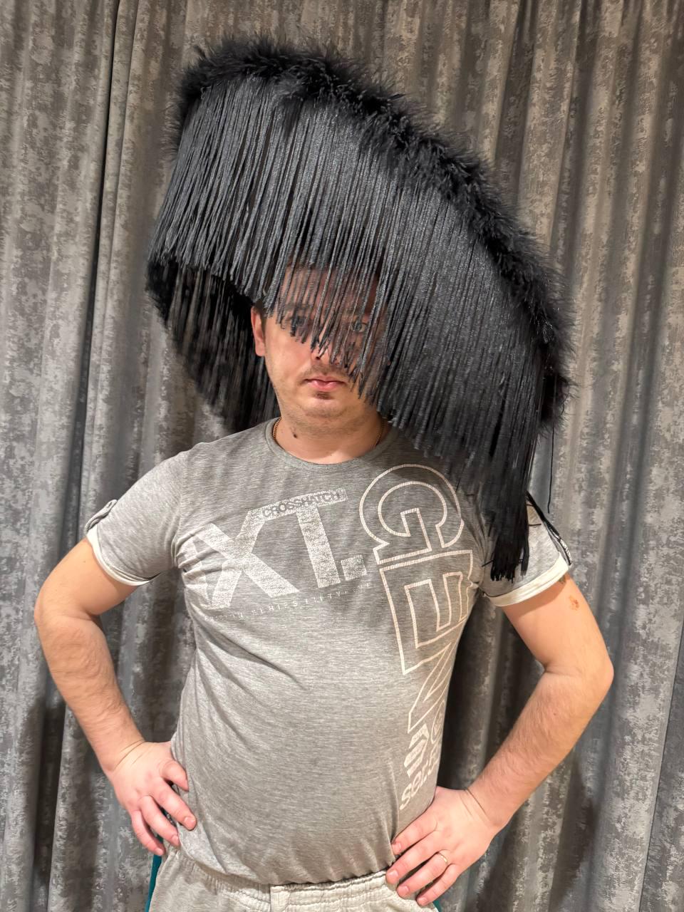 May include: A large, black, fringed hat obscures the face of a person wearing a gray t-shirt. The hat's fringe hangs down, partially covering the eyes. The t-shirt has white text and the words "CROSSHATCH" and "XL" are visible.