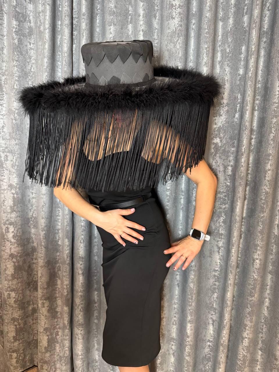 May include: A black wide-brimmed hat with a black feather trim and fringe. The hat is made of a textured material and has a unique design.