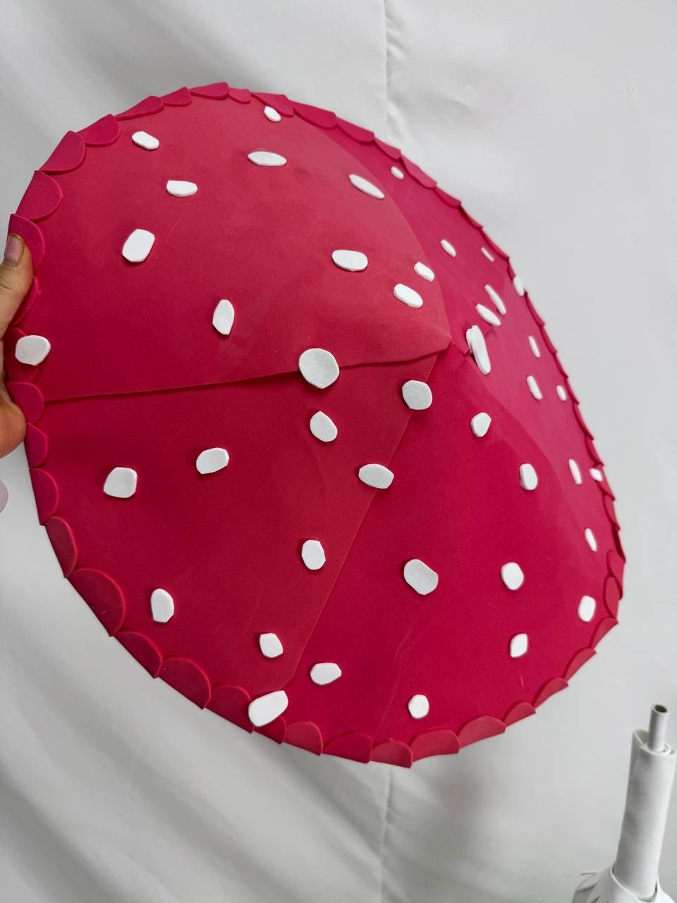 May include: A large, red foam mushroom with white polka dots. The mushroom is made of foam and has a scalloped edge.
