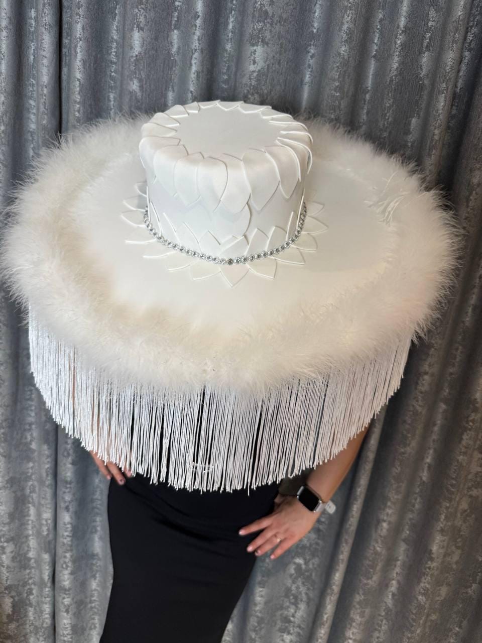 May include: A large white hat with a wide brim and a feathered trim. The hat is decorated with a white, sculpted design and rhinestones.