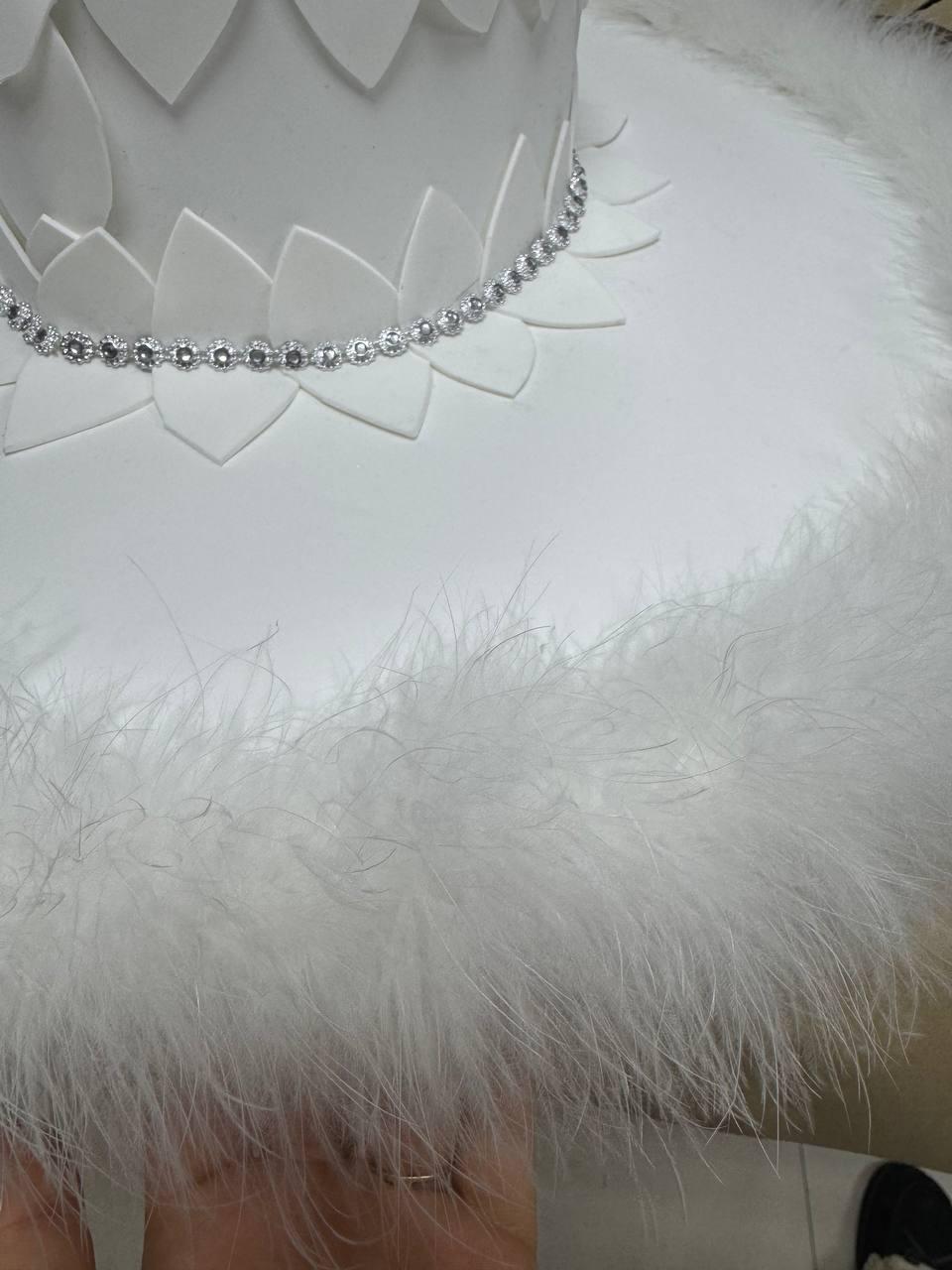 May include: White cake with a white feather trim and a silver rhinestone trim.
