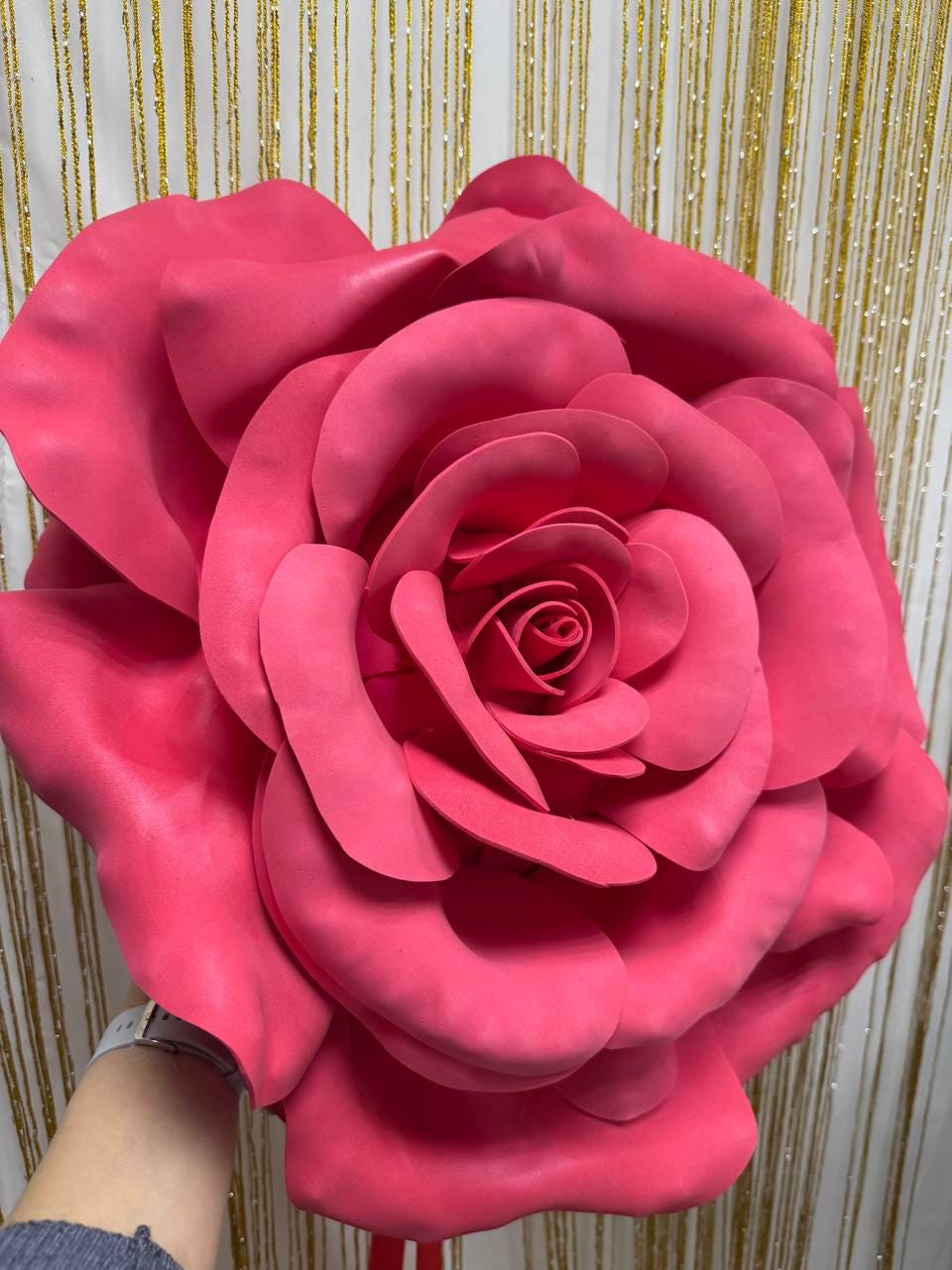 May include: A large, vibrant pink rose made of a soft material. The petals are layered, creating a full, open bloom. The rose is a bright, eye-catching decoration, perfect for events or home decor.