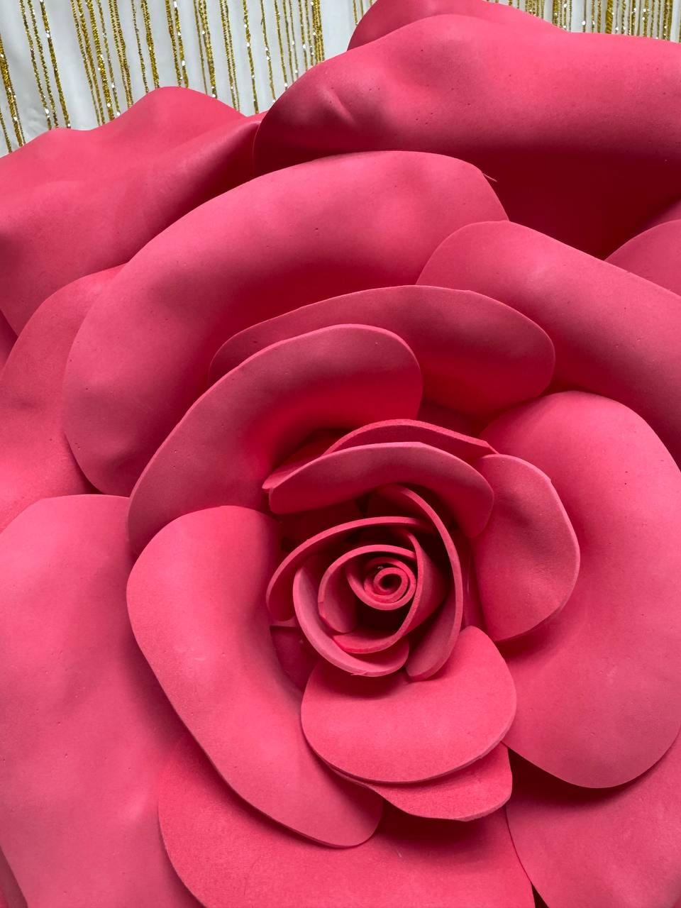 May include: Close-up of a large, vibrant pink rose. The petals are layered and textured, creating a full, dimensional bloom. The rose's center is tightly wound, and the outer petals are gently curved. The overall effect is a bold, eye-catching floral design.