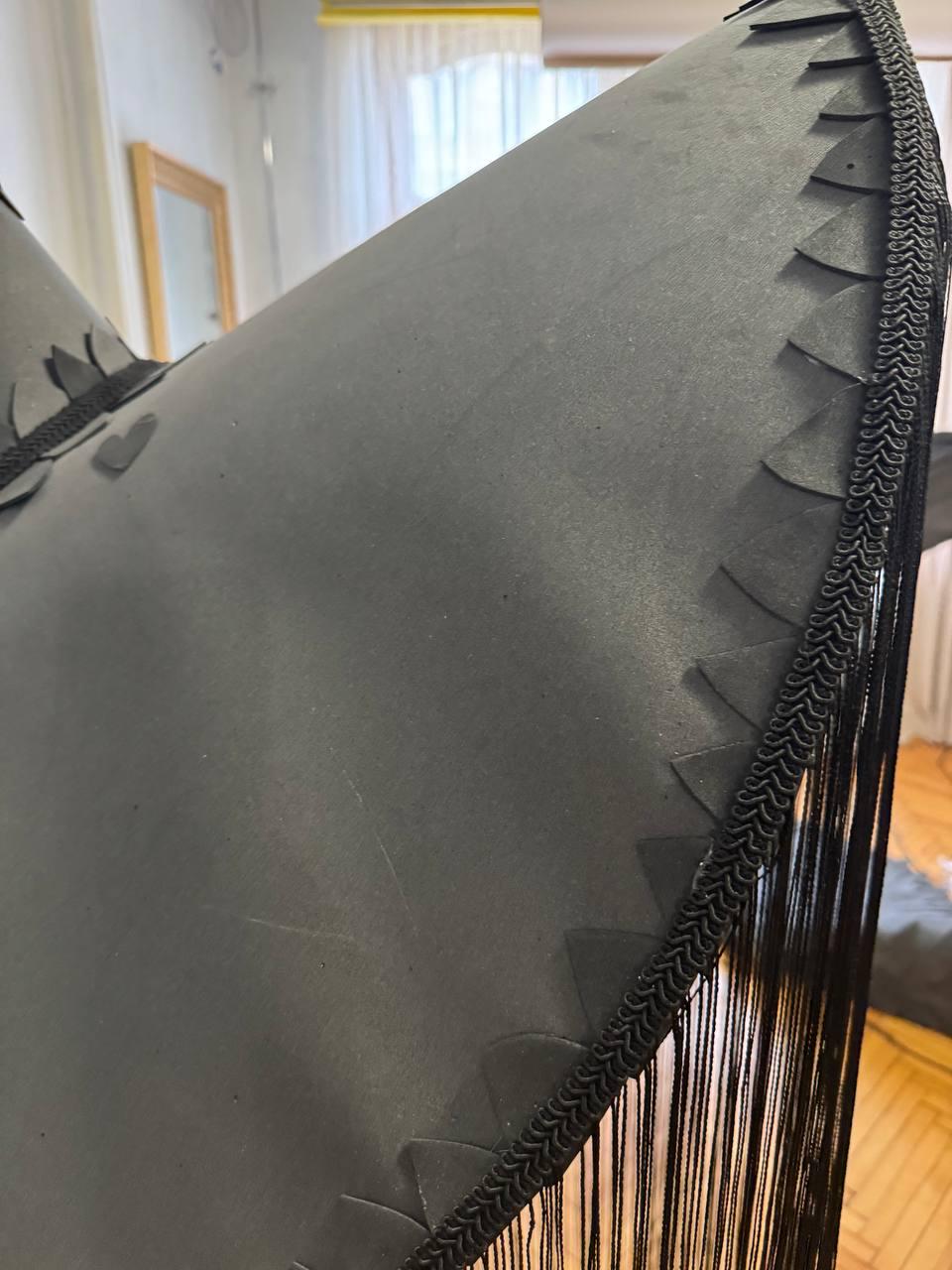 May include: Black sombrero with a fringe trim and a scalloped edge. The hat is made of a soft, pliable material.