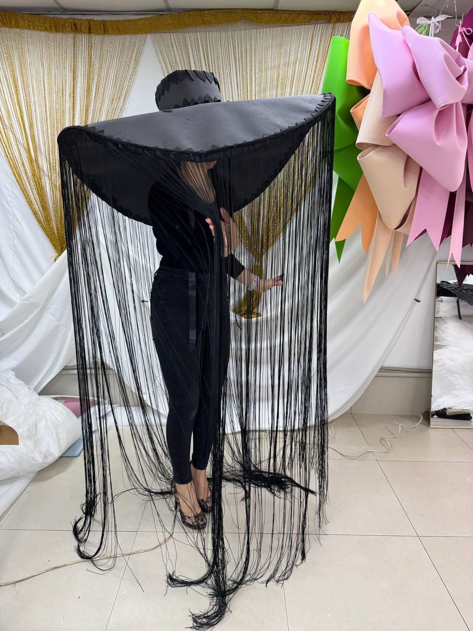 May include: A large black hat with a wide brim and long fringe. The hat is made of a soft, pliable material and has a simple, elegant design.