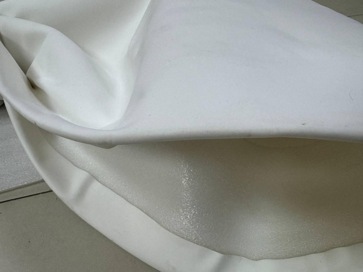 May include: White fabric with a textured surface. The fabric is folded in on itself, creating a layered effect.