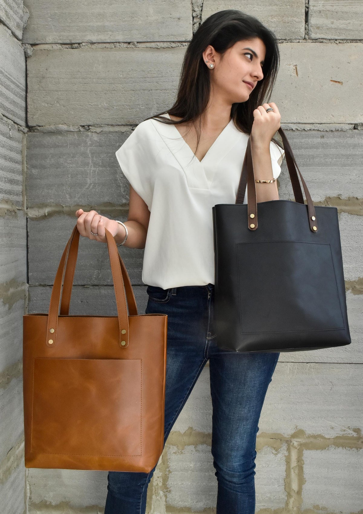 May include: Two leather tote bags with a front pocket. One bag is brown and the other is black.