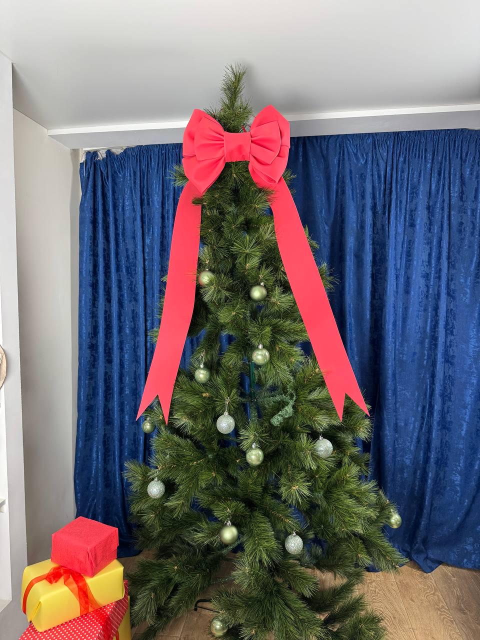 May include: A decorated Christmas tree with a large red bow at the top and red ribbon streamers. The tree is adorned with silver and green ornaments. Several wrapped gifts are at the base of the tree.