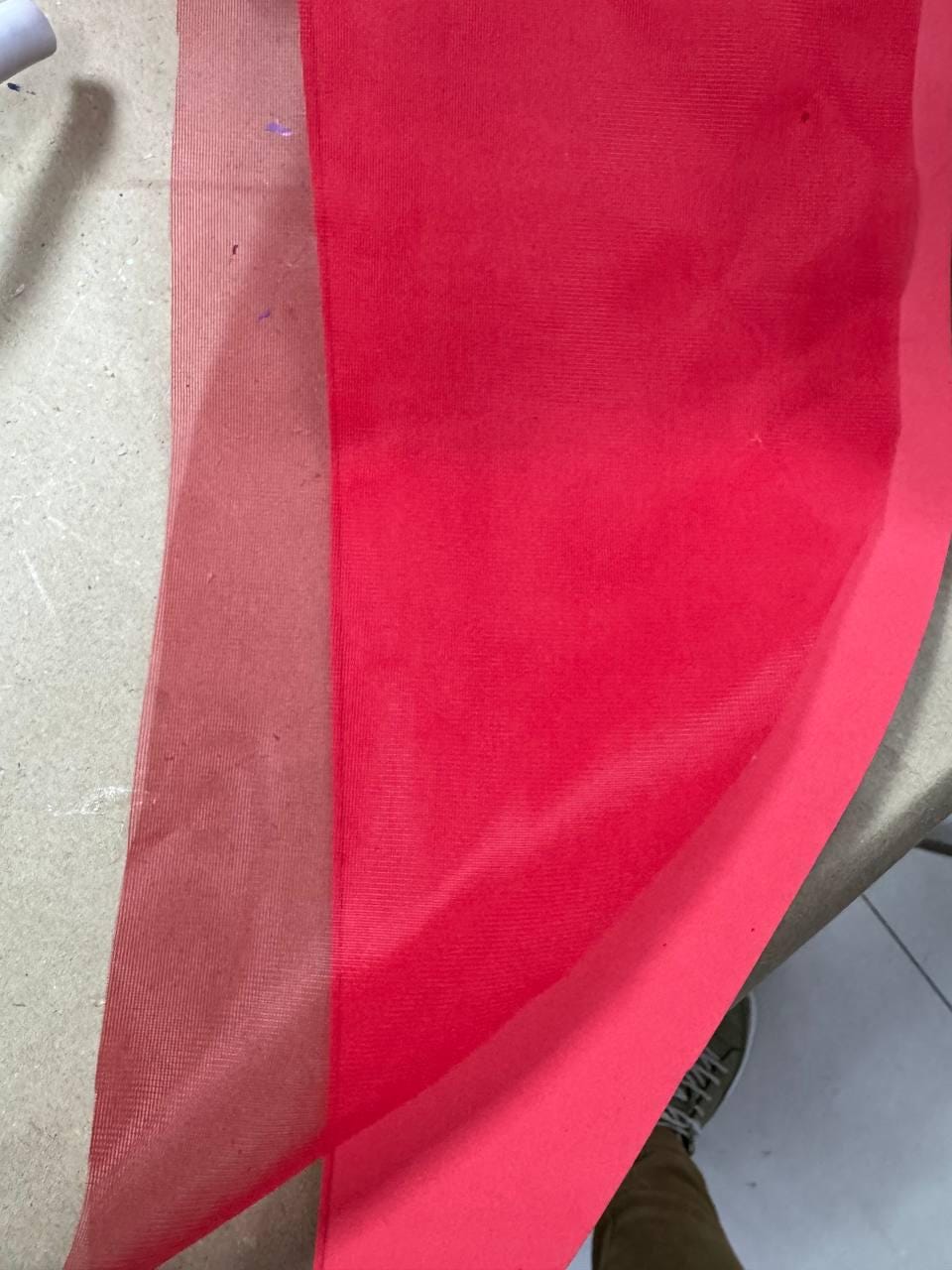 May include: A close-up of three layers of fabric in shades of red. The layers include a sheer, light red mesh, a solid, vibrant red fabric, and a darker red fabric. The fabrics are layered on top of each other.