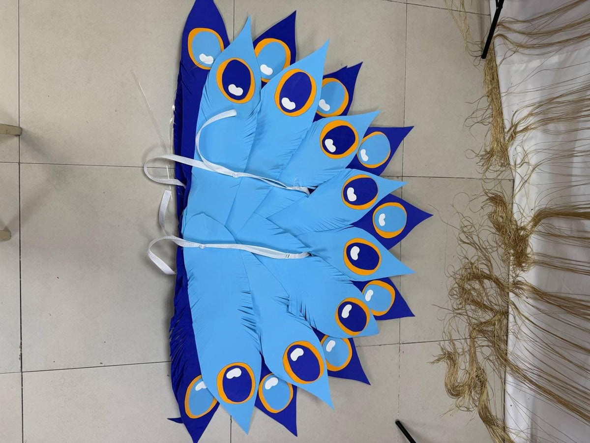 May include: A fan-shaped decorative piece resembling a peacock's tail. The design features large, light blue feathers with dark blue edges and eye-like patterns in white, dark blue, and orange. White ribbons are attached for hanging or securing the piece.