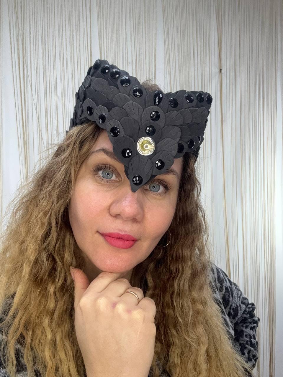 May include: A black headpiece with a feathered design, adorned with black gems and a central gold-colored emblem. The headpiece is worn on the head.