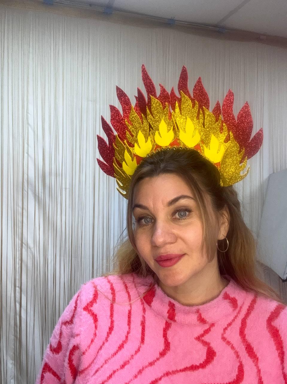 May include: A decorative headpiece resembling flames, featuring red, yellow, and gold glitter accents. The crown is designed with a flame-like shape, perfect for costume parties or themed events. The headpiece is a vibrant accessory.