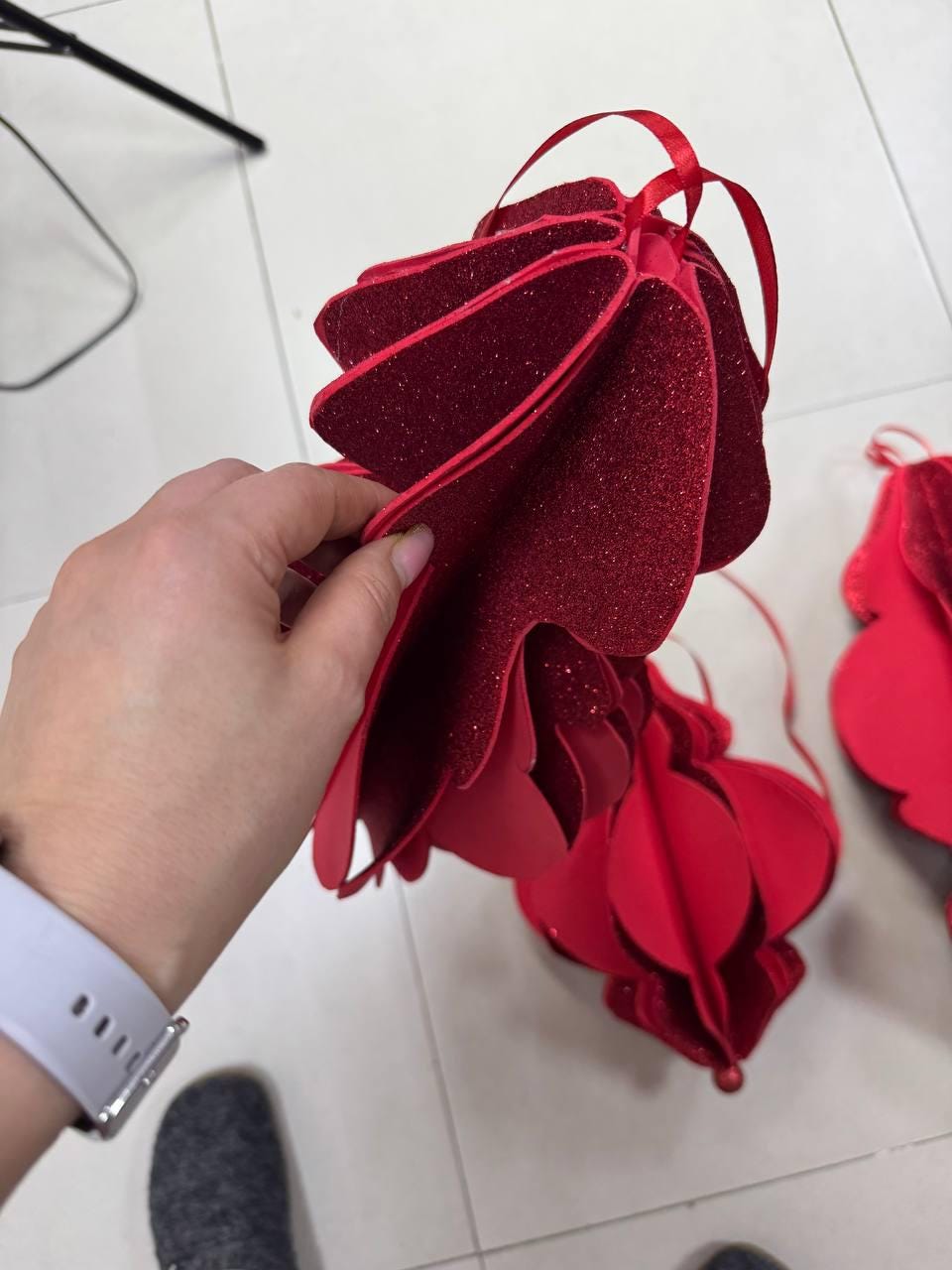 May include: Red, layered, glitter-covered ornament with a ribbon for hanging. The ornament has a unique, dimensional design, with multiple layers creating a textured appearance. The ornament is a festive decoration.