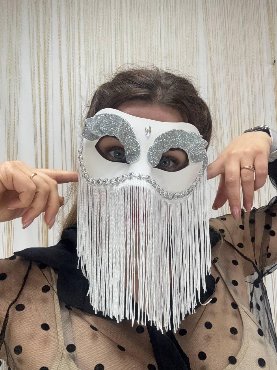 May include: White masquerade mask with silver glitter accents and a fringe of white strands. The mask features a decorative design around the eyes and a small jewel. A unique accessory for costume parties or themed events.