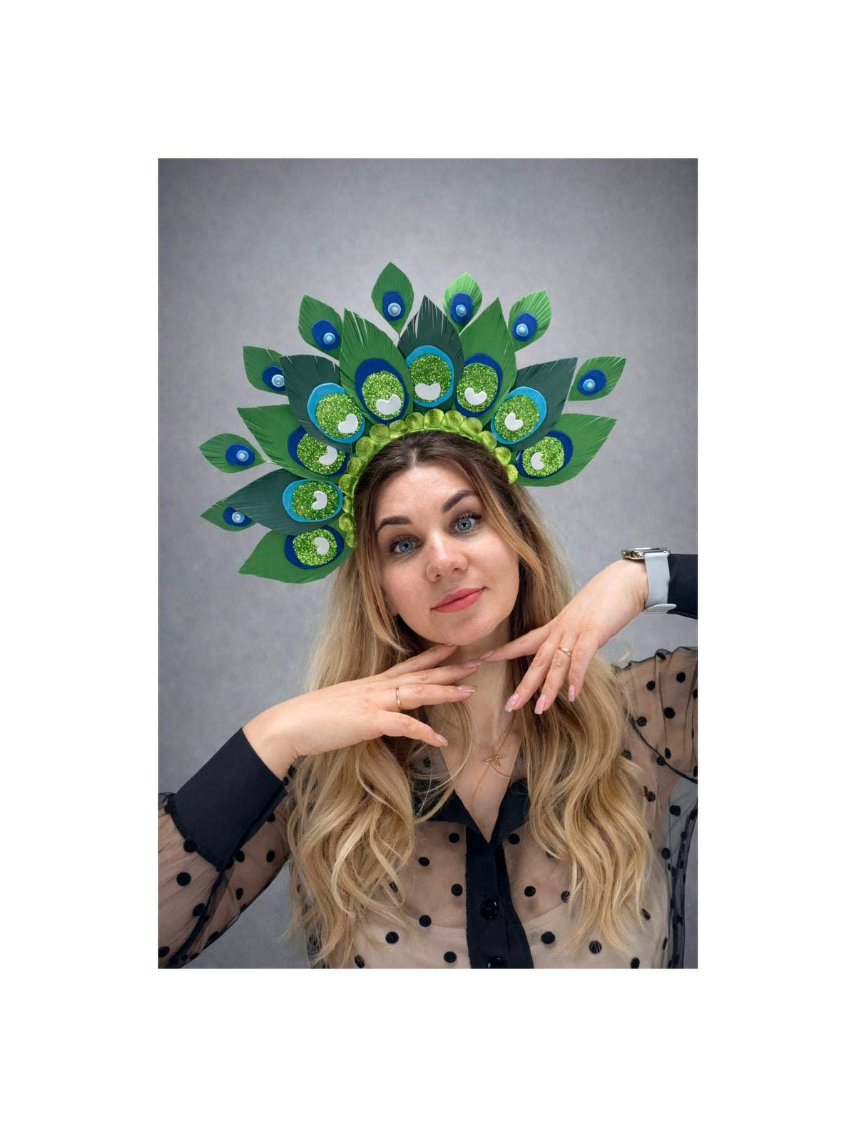 May include: A vibrant peacock feather headdress with green, blue, and glitter accents. The headpiece features large, stylized feathers and is designed to be worn on the head. The colors are bright and eye-catching, perfect for a costume or special event.