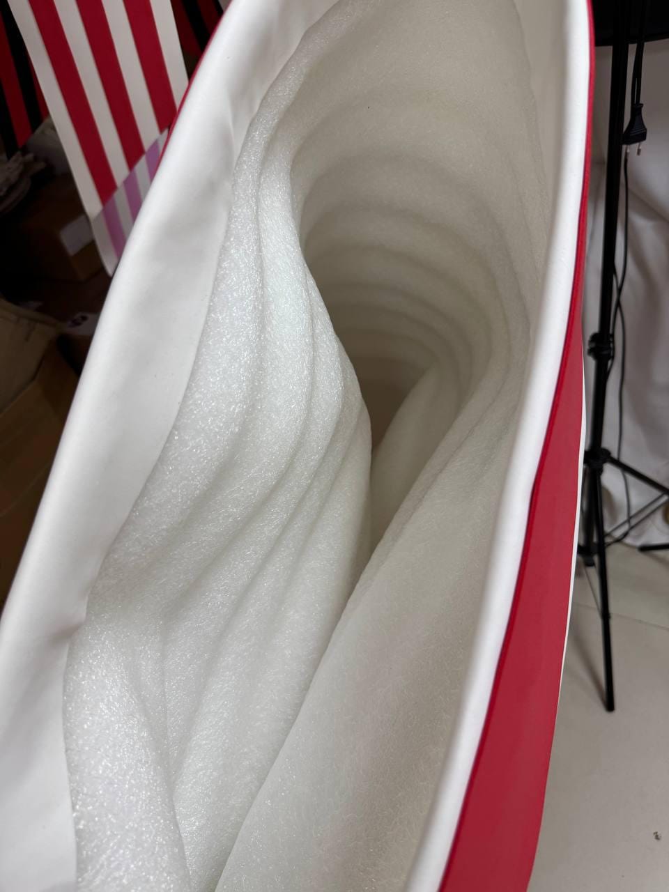 May include: A red and white container with a white interior filled with white foam padding. The container has a red exterior with a white trim. The foam padding is layered and fills the interior of the container.