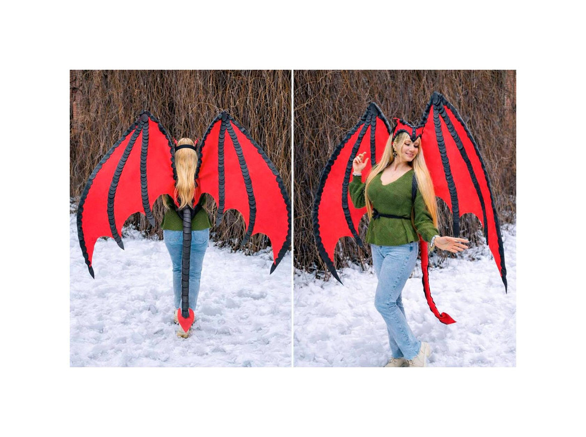 May include: Red and black dragon wings with a matching tail and headpiece. The wings are large and spread out, with a black trim and a red interior. The tail is long and red, and the headpiece has small horns. The costume is worn by a person in a green top and blue jeans.