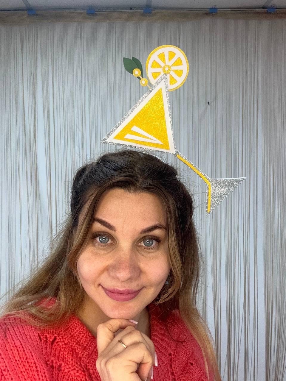 May include: A whimsical, handmade cocktail-themed headpiece. The headpiece features a yellow triangle with silver glitter trim, a yellow lemon slice, and a silver glitter stem. The design is a fun accessory for parties or themed events.