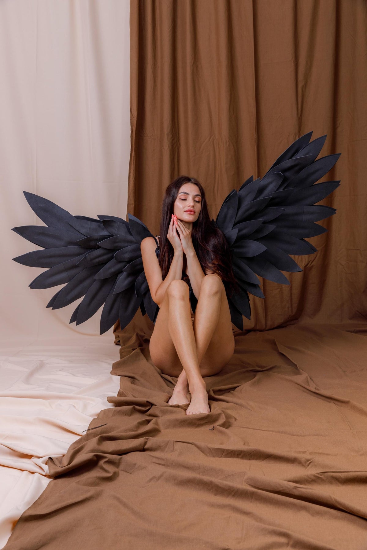 May include: Large, expansive black wings featuring layered, feather-like segments arranged in a wide, pointed fan shape. The wings are constructed with individual matte black panels that overlap to create a textured, structural appearance.