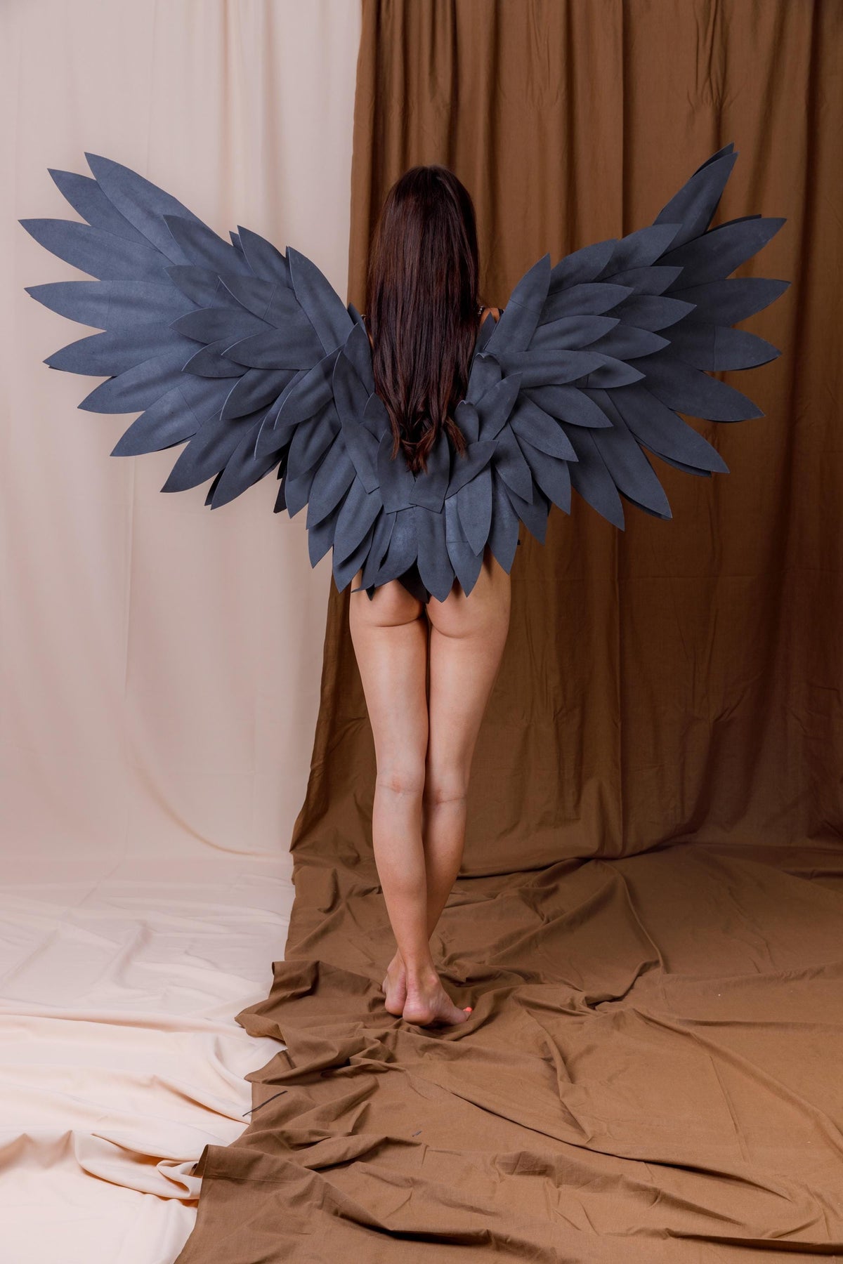 May include: A pair of large, dark gray wings constructed from layered, feather-shaped pieces. The wings are wide and span horizontally, featuring a structured design with multiple rows of overlapping, pointed segments that mimic the appearance of bird wings.