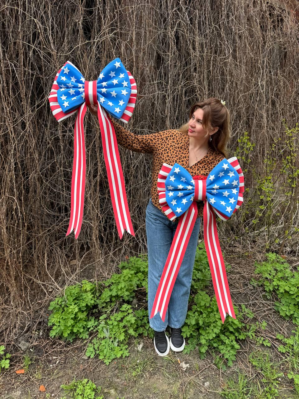 May include: Two large decorative bows with a patriotic design. The bows feature a blue center with white stars, red and white striped ribbons, and red and white striped edges. Perfect for Independence Day or other patriotic events.