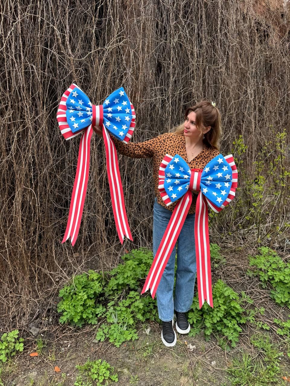 May include: Two large decorative bows with a patriotic theme. The bows feature a blue center with white stars, red and white striped edges, and long red and white striped ribbons. Perfect for Independence Day or other patriotic events.