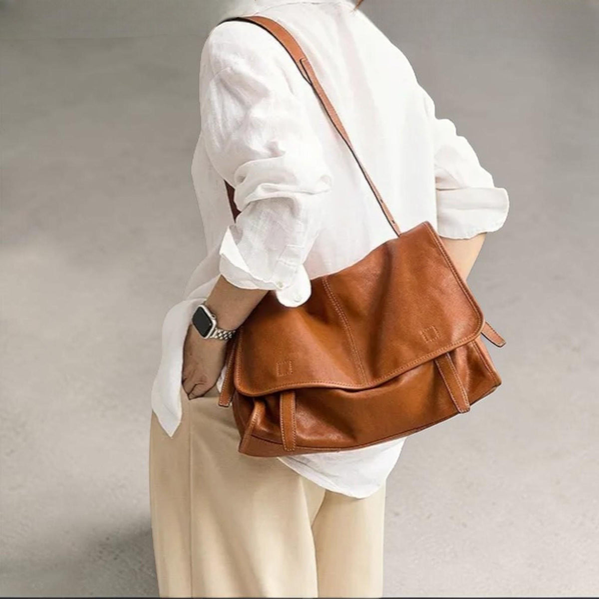May include: A brown leather messenger bag with a flap closure and adjustable shoulder strap. The bag has a rectangular shape and a worn, textured appearance. The bag is worn over the shoulder.