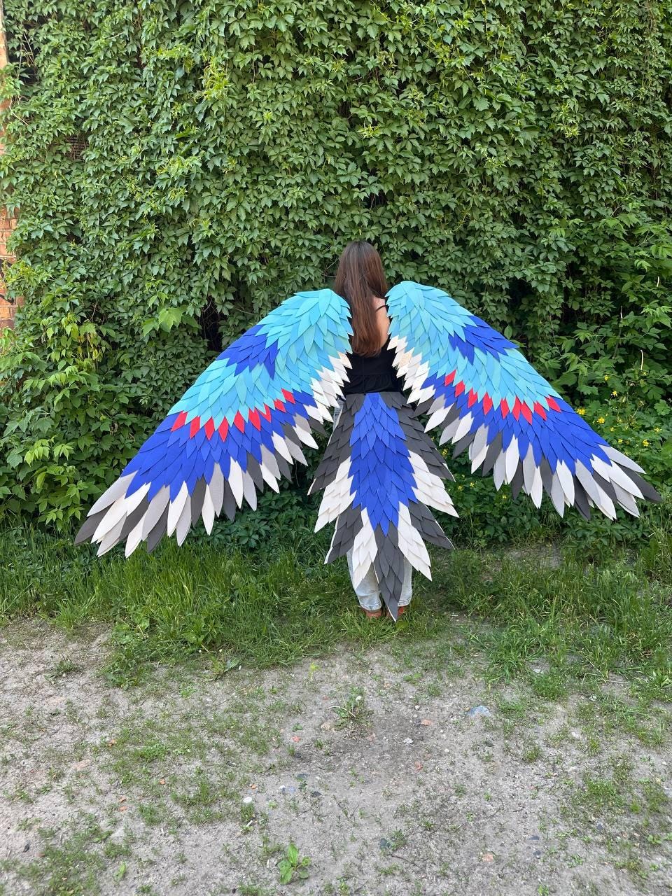 May include: Large decorative bird wings and a matching tail piece featuring layered feathers in shades of bright blue, dark blue, red, white, and gray. The wingspan is wide, with individual feather-shaped cutouts arranged in a gradient pattern.